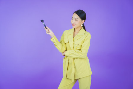 Portrait beautiful young asian woman with make up brush cosmetic on color backgroundの写真素材