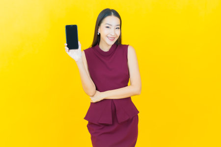 Portrait beautiful young asian woman smile with smart mobile phone on color backgroundの写真素材