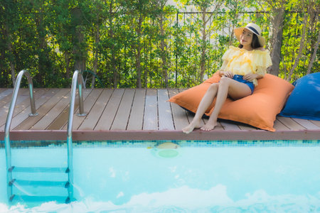 Portrait young asian woman happy smile relax around outdoor swimming pool in hotel resort for travel vacationの写真素材