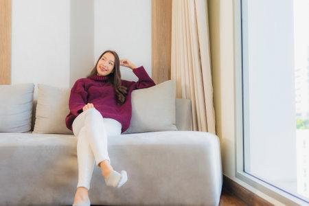 Portrait beautiful young asian woman smile relax on sofa in living room interiorの写真素材