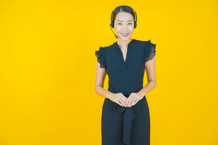 Portrait beautiful young asian woman with call center customer care service center on yellow color backgroundの写真素材