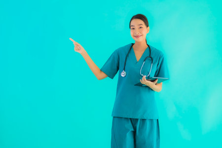 Portrait beautiful young asian doctor woman use smart tablet device on blue isolated backgroundの写真素材