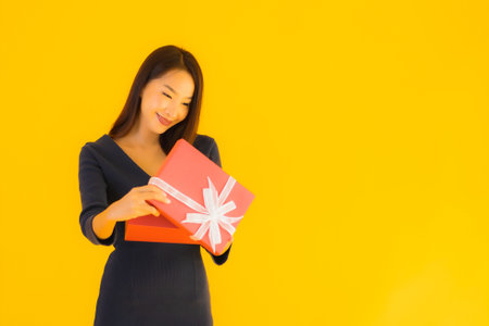 Portrait beautiful young asian woman with giftbox on yellow isolated backgroundの写真素材