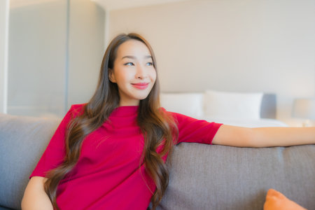 Portrait beautiful young asian woman relax smile on sofa in living area at bedroom interiorの写真素材