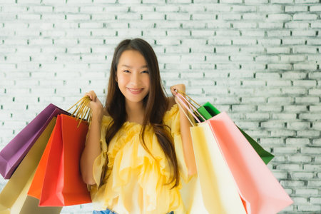 Portrait young asian woman holding colorful shopping bag with happy smileの写真素材