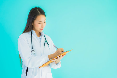 Portrait beautiful young asian doctor woman with empty card billboard banner on blue isolated backgroundの写真素材