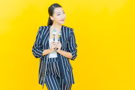 Portrait beautiful young asian woman smile with spoon and fork on color backgroundの写真素材