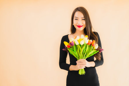 Portrait beautiful young asian woman with color flower on color isolated backgroundの写真素材
