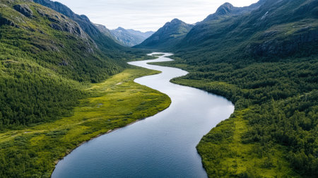 A breathtaking aerial view of winding river surrounded by lush greenery and mountainsの素材