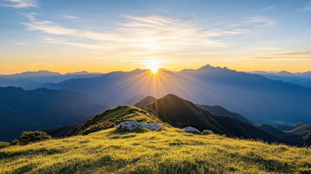 Golden sunrise over mountain range, illuminating grassy hilltops with vibrant raysの素材