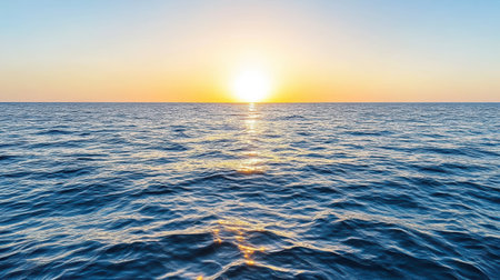 Sunrise over calm ocean waters, reflecting warm colors and creating serene atmosphereの素材