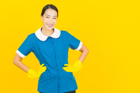Portrait beautiful young asian woman maid and housekeeping smile with action on yellow color background