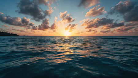 Serene sunset sea horizon ocean waves golden light calm sky cloudsの素材