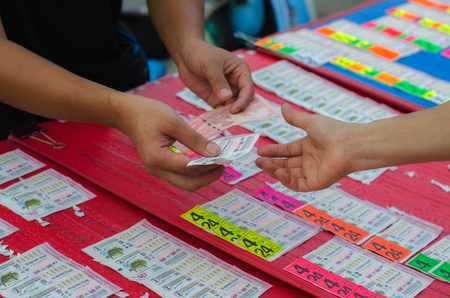a man is choosing and buying Thai government lottery ticket in a marketのeditorial素材