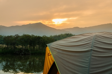 tent set on the grassland of mountain in the sunriseの写真素材