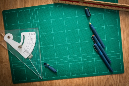 Green Cutting mats , Pen drawings , adjust angle tool , scale ruler  on the wood background