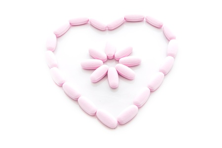 pink pills Arranged in a Heart on white background