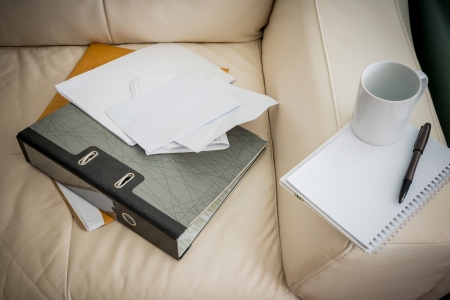 closeup coffee cup, pen, notebook , document file is on white sofaの写真素材
