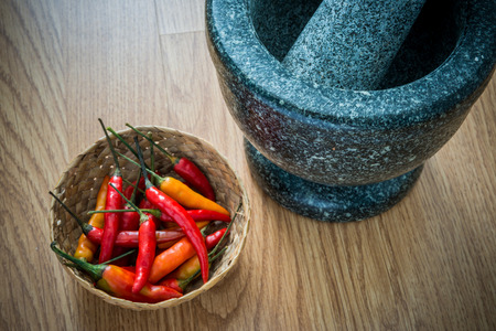 Red Hot Chili Peppers in wooden bowl and Mortar over wooden tableの写真素材