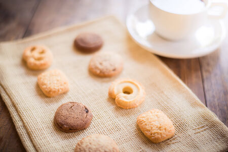 Cup of coffee and Many shapes biscuit on sackcloth and wooden table