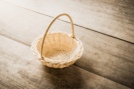 Empty wicker basket isolated on wooden table backgroundの写真素材