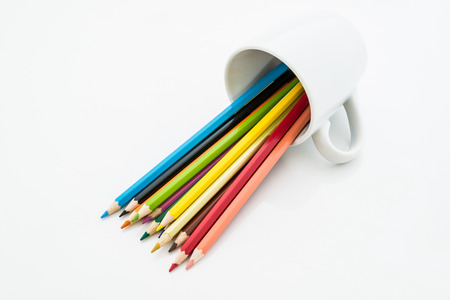 stack of colored pencils and white coffee cup on white backgroundの写真素材