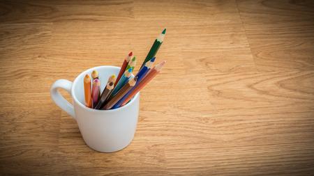 Color pencils in white coffee cup on wooden backgroundの写真素材