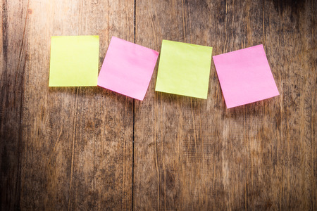 Wooden background with four blank colorful sticky notes