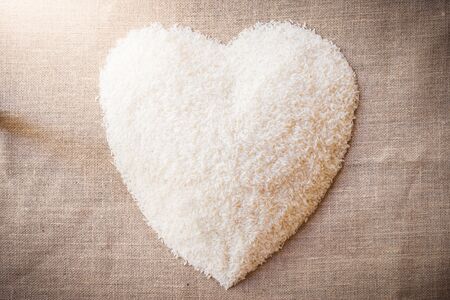 Rice laid out in a heart shape on the sackcloth. The view from the topの写真素材