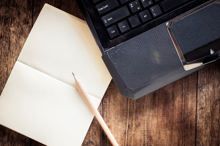Blank notebook with pencil on Laptop and wooden table. The view from the topの写真素材