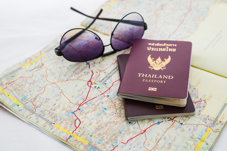 Passport on map and sunglasses. Focus at THAILAND Passport Book