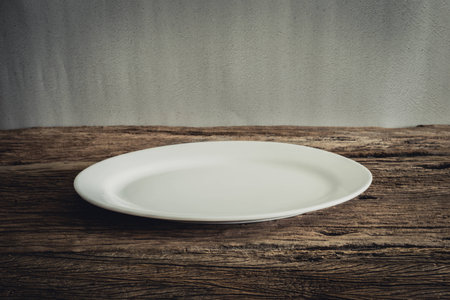Empty Plate on wooden tabletop against grunge wall. vintage toneの写真素材