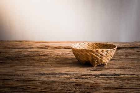 Empty wicker Basket on wooden tabletop against grunge wall. vintage tone