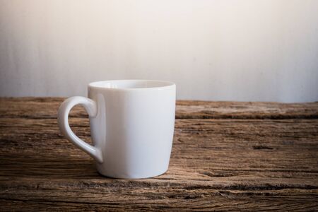 white mug on wooden tabletop against grunge wall. vintage toneの写真素材