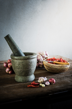 dry chili pepper and red onion and garlic and stone mortar on an old wooden background. vintage toneの写真素材