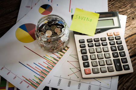 many coins in a money jar with saving label on jar, on office table. saving conceptの写真素材