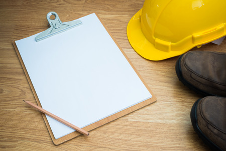 Yellow Safety Helmet Hat and clipboard and pencil on Wood backgroundの写真素材