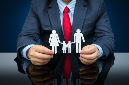 people, charity and care concept - close up of businessman hands holding paper family. isolated on white background with clipping pathの写真素材