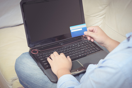 close up of man with laptop computer and credit card at home. technology, leisure, shopping, banking and lifestyle conceptの写真素材