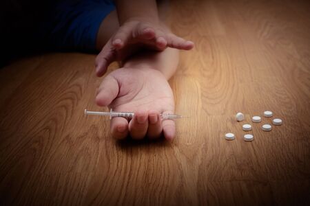 overdose male drug addict hand, drugs narcotic syringe on floorの写真素材