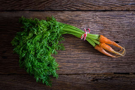 fresh carrots bunch with green leaves on wooden background Vegetable Foodの写真素材