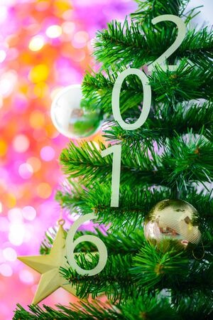 Multicolor Christmas background of de-focused lights with decorated Christmas tree. Text 2016 on...