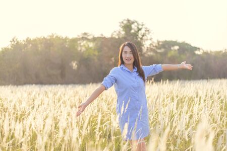 Portrait of the young beautiful smiling woman outdoors in the grass fieldの写真素材