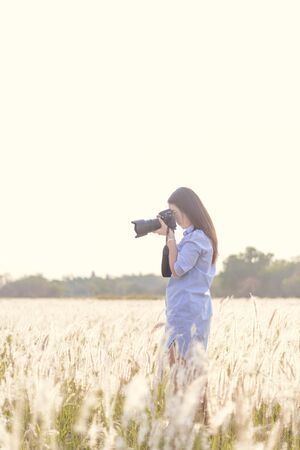 Portrait of the young Female photographer outdoors in the grass fieldの写真素材