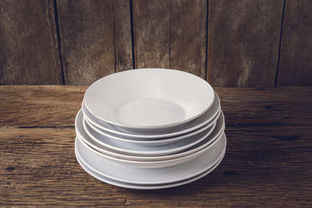 Multiple white dish, plate on grunge wooden tableの写真素材