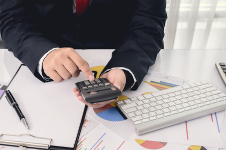 files and folders and businessman in background with calculator in handsの写真素材