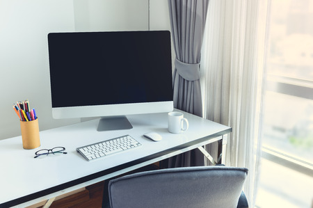 Blank computer desktop with keyboard, diary and other accesories on white table in morningの写真素材