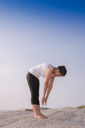 young woman practicing yoga on the beach at sunriseの写真素材