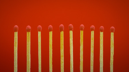 pile of matchsticks arrange in a row on a red background.の写真素材