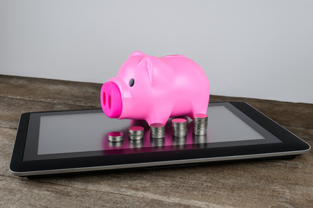 Piggybank and row of coin money on tablet in money saving, online Banking, internet Banking conceptの写真素材